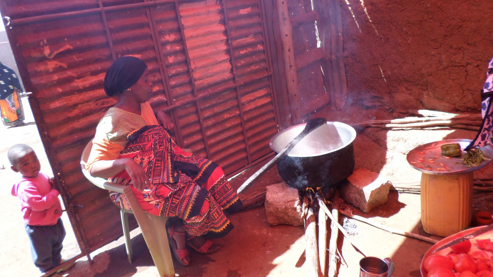 Eine Frau in der informellen Siedlung Kibera in Nairobi, Kenia, bereitet ein Essen auf einem traditionellen Steinherd zu. Brennholz erzeugt erhebliche Mengen an Schadstoffen und macht Menschen anfällig für Atemwegserkrankungen.