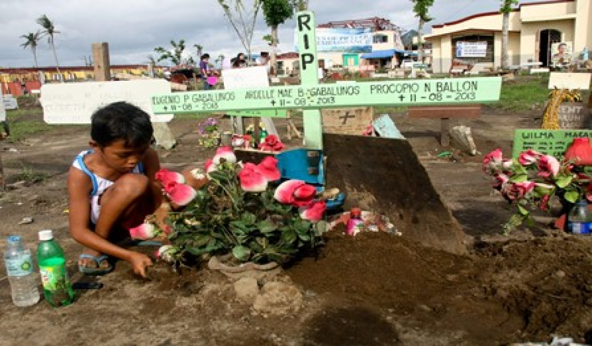 Ein Kind pflegt das Grab der Opfer des Super-Taifuns Yolanda.